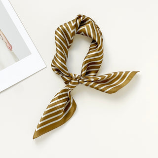 Luxurious silk bandana scarf with bronze and white geometric pattern, elegantly tied in a knot against neutral background
