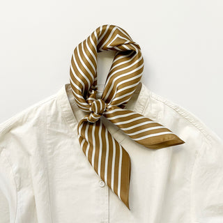 Luxurious bronze and white striped silk bandana scarf tied elegantly around a white shirt collar, showcasing its versatile styling