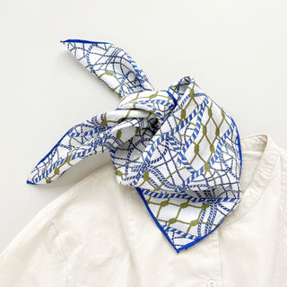 Silk bandana with white background, blue nautical rope pattern and gold accents, styled in knot over white shirt collar with blue border trim
