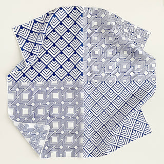 Square silk scarf with blue and white geometric patterns featuring chevrons and squares, arranged in a modern design with hand-rolled edges
