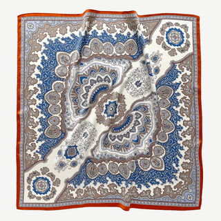 Silk scarf with blue and orange baroque pattern featuring intricate paisley designs and medallions on light grey background with vibrant border