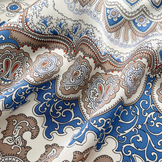 Close-up of a Silk scarf with intricate baroque pattern in blue, orange and beige tones, featuring ornate paisley designs.