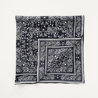 Square black silk scarf with white paisley pattern and hand-rolled edges, featuring elegant border stripes and intricate detailing