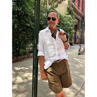 Man wearing a black and white abstract spot silk neckerchief with a white linen shirt and tailored shorts, styled for a timeless smart casual summer look.