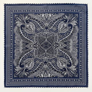 Navy silk scarf featuring intricate white paisley pattern with symmetrical design and decorative hand-rolled edges, displayed flat to show complete square shape