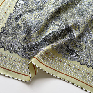 Navy and gold silk scarf featuring intricate paisley pattern with decorative border, hand-rolled edges, and luxurious twill texture