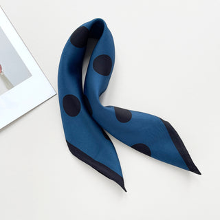 Yale blue silk scarf with large black polka dot pattern and hand-rolled edges, elegantly draped on white background