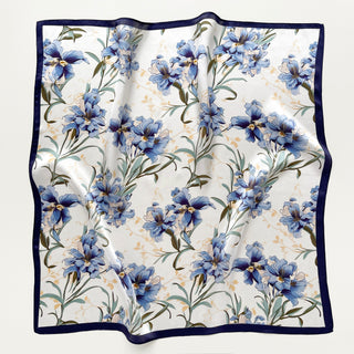Square silk scarf with blue bell floral pattern on white background, bordered with navy blue trim, showing lustrous fabric texture