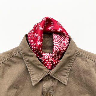 Red silk bandana with white paisley and polka dot patterns elegantly tied around the neck of a khaki button-up shirt