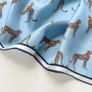 Sky blue silk scarf with leopard print pattern featuring cheetahs on a luxurious twill fabric with navy and white border trim
