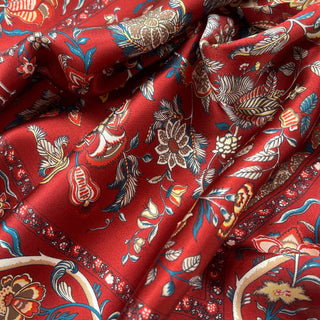 Red silk scarf with vintage floral pattern featuring blue, cream, and gold botanical designs with delicate detailing and silky sheen texture