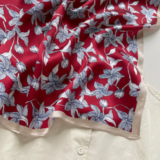 Luxurious red silk bandana scarf with elegant blue and white floral pattern, featuring a light cream border and silky texture