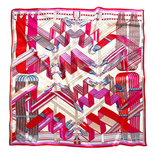 Square silk scarf with geometric city maze design in vibrant magenta, red, and beige tones with architectural patterns and a decorative red border