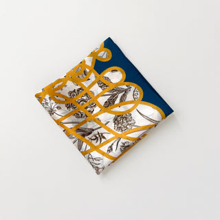 Luxury silk scarf with botanical sketches on ivory background, gold baroque ribbon pattern, and deep teal border, folded into a square