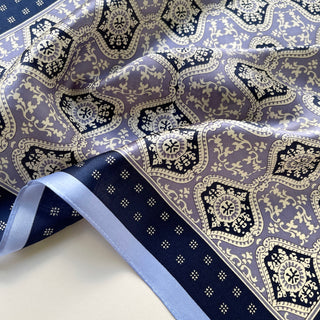 Luxurious silk scarf with geometric floral pattern in navy blue and lavender, featuring ornate medallions and delicate border details