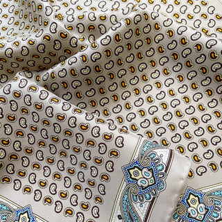 Taupe silk scarf with small paisley pattern in gold, brown and white, featuring decorative blue ornamental border design with hand-rolled edges
