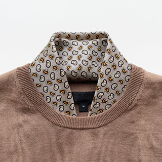 Taupe silk paisley neckerchief styled with a brown sweater, showcasing detailed gold and blue paisley pattern on luxurious silk with hand-rolled edges