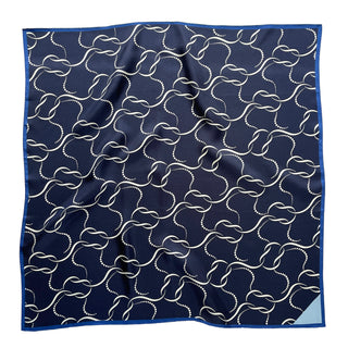 Navy blue silk scarf with white chain-link pattern, royal blue hand-rolled edges and light blue corner detail, displayed flat showing luxurious texture