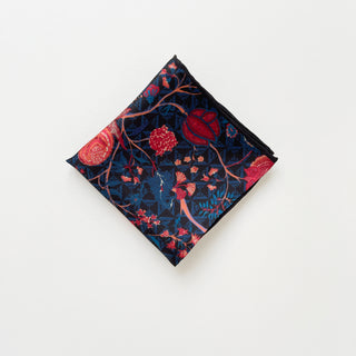 Luxury silk bandana with navy blue background featuring vibrant red floral pattern and hand-rolled edges, displayed in diamond shape