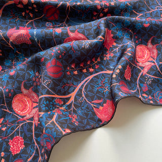 Luxurious silk scarf with navy blue background featuring vibrant red and pink floral patterns, showcasing hand-rolled edges and smooth silk twill texture.