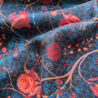 Close-up of silk scarf with navy blue background featuring vibrant red floral pattern and delicate twill texture showing natural folds