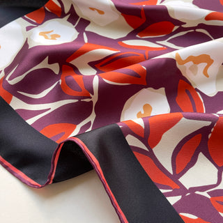 Luxurious silk scarf with burgundy purple, red and cream floral pattern, featuring hand-rolled edges and smooth twill texture