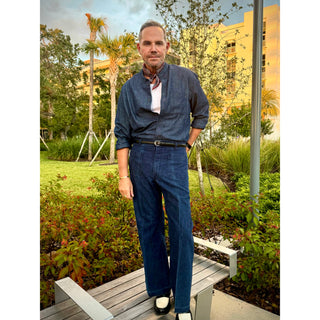 Man wearing a red and navy tone patterned silk square scarf from LuluLane in a whole denim outfit showcasing a polished smart casual look.