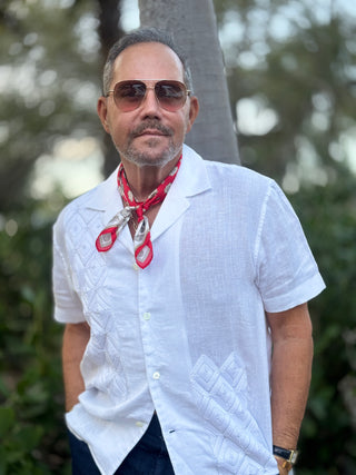 Red and white silk neckerchief styled with crisp white linen shirt, showcasing the decorative imperial crest pattern against outdoor greenery