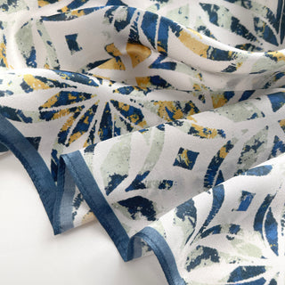 Silk bandana scarf with artistic dusty blue, yellow and pale green floral pattern on white background, featuring blue trim edge detail