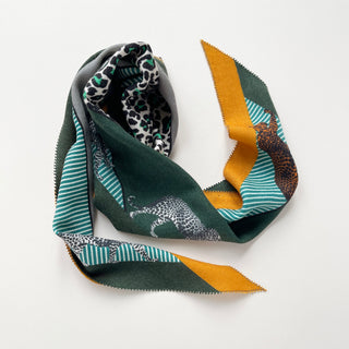 Diamond-shaped cashmere silk scarf featuring cool palette with green, turquoise, mustard, and gray, adorned with leopard prints and stripe patterns.