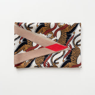 Folded beige-brown cashmere silk scarf featuring tiger pattern with red accents against ivory background, showing luxurious texture and edge detail