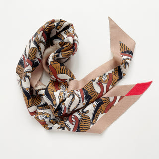 Diamond-shaped cashmere silk scarf with tiger pattern in beige, brown, and red, displayed draped with elegant folds showing both border and center design.