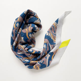 Luxurious diamond-shaped scarf with blue tiger pattern on mauve background, featuring yellow accent and light gray trim, elegantly draped to showcase texture.