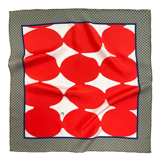 Square silk scarf with bright orangey-red mod circles on white center, navy border, and green diamond pattern edge, displaying luxurious sheen