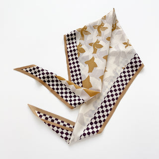 Elegant beige cashmere silk scarf featuring Art Deco stylized golden birds pattern and brown-cream checkerboard border, displayed in a flowing arrangement