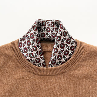 Geometric silk bandana scarf with red, black and white pattern styled with camel sweater, showing intricate heritage design pattern