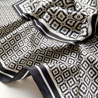 Luxurious black and white silk scarf with geometric floral pattern, featuring hand-rolled edges and elegant monochrome design