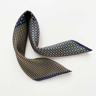 Navy blue silk scarf with patchwork pattern featuring geometric circles, medallions and paisley designs in gold and light blue tones with hand-rolled edges