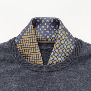 Navy blue silk scarf with intricate geometric and paisley patterns in gold, blue and yellow, styled with a gray sweater as a neckerchief