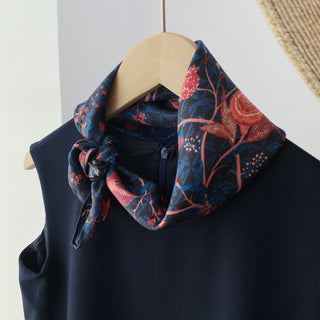 Midnight blue silk scarf with vibrant red floral pattern tied stylishly on a navy garment, displaying luxurious hand-rolled edges and twill texture