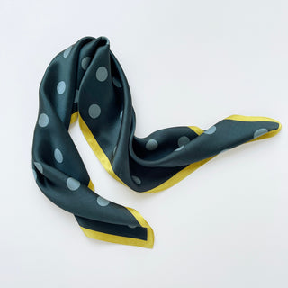 Teal green silk scarf with light blue polka dots and bright yellow border, elegantly draped to showcase its smooth texture and 65cm square design