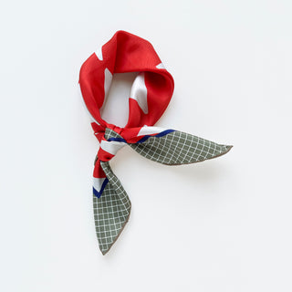 Retro mod silk scarf tied in loose knot featuring vibrant orangey-red with white dots and deep green checkered pattern on a white background