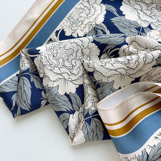 Luxurious silk square scarf with white peony pattern on navy blue background, featuring elegant blue and gold border trim