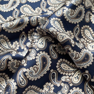Close-up of navy blue silk scarf with cream and brown paisley pattern, showing the smooth, luxurious fabric texture with elegant folds