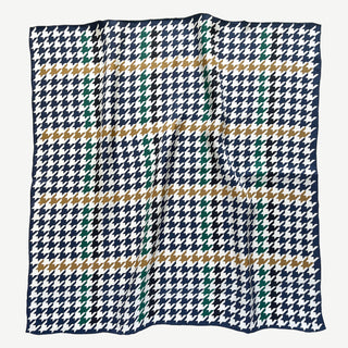 Luxury square silk scarf with navy, green, and gold houndstooth pattern on white background with hand-rolled edges