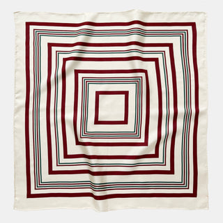 Luxury silk scarf with modern geometric square pattern featuring deep burgundy and green concentric squares on cream white background with hand-rolled edges.