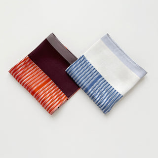 Two Lunar Peaks silk scarves displayed side by side - tangerine with burgundy color blocking and French blue with white, both featuring chevron patterns.