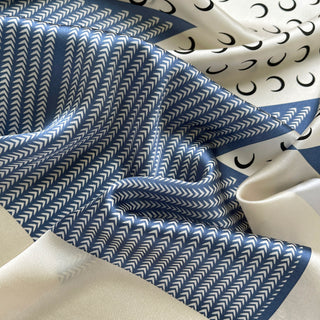 Lunar Peaks silk scarf featuring French blue chevron pattern with cream accents and crescent moon design, showing luxurious fabric texture and drape