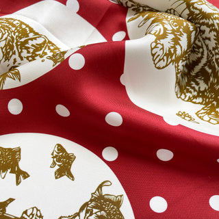 Luxurious silk scarf with red background, white polka dots and paw print pattern in gold, showcasing elegant hand-rolled edges and twill texture