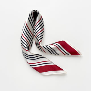 Silk bandana scarf with diagonal navy and red stripes on white background, elegantly arranged to show shimmering texture and geometric pattern
